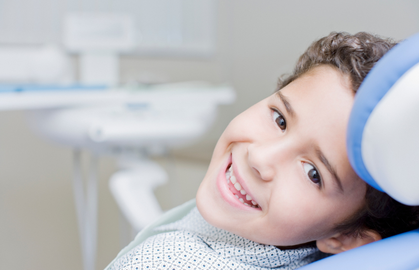 Child smiling in orthodontist chair after receiving emergency orthodontic treatment