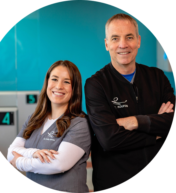 Doctor's Michael Koufos and Emily Koufos-Radford standing back to back and smiling.