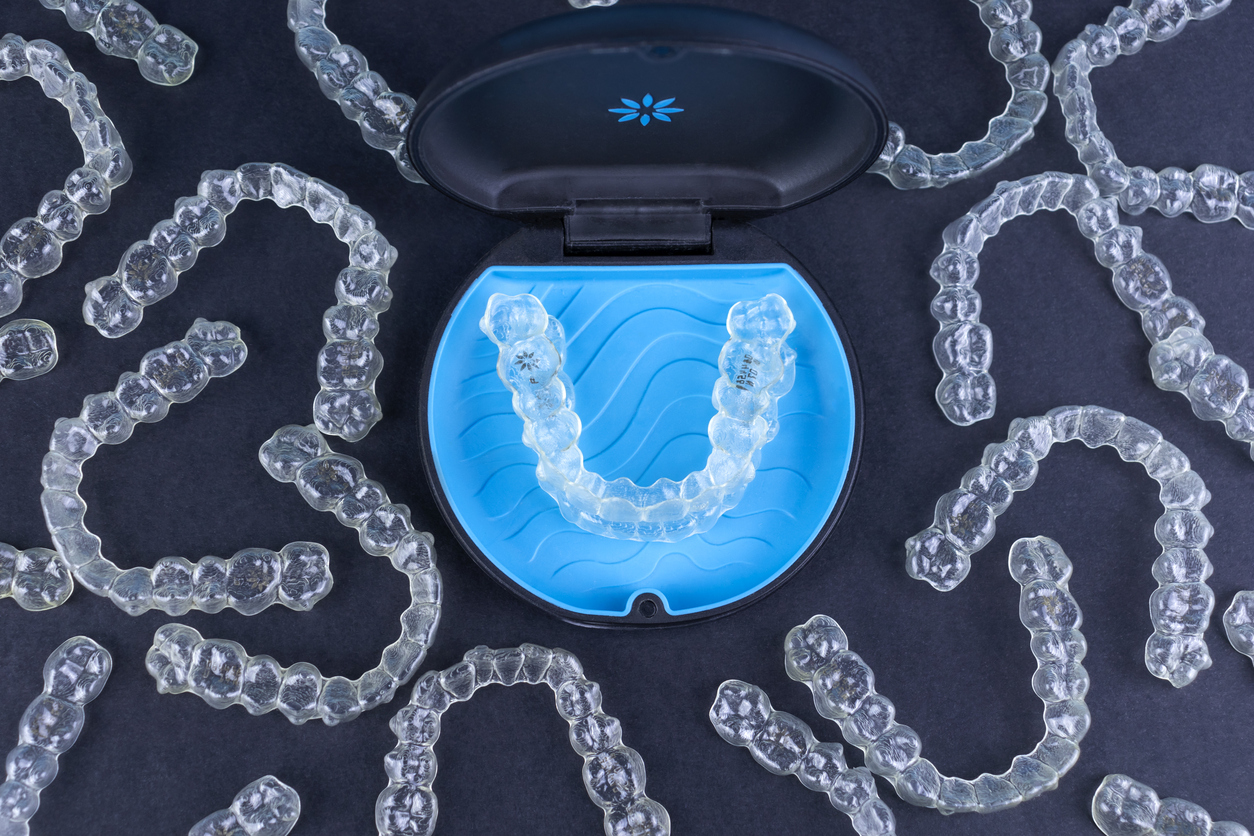 Sleek Invisalign image with an Invsialign aligner in a blue tray surrounded by aligners