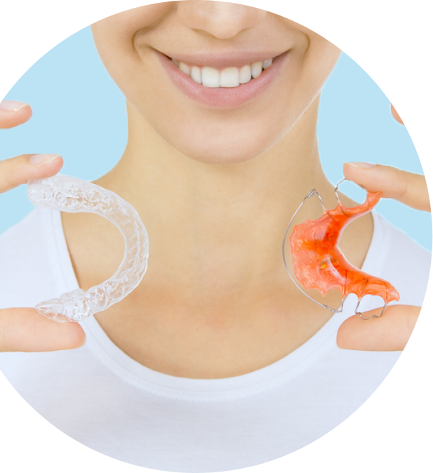 A white lady holding clear and metal retainers in a white shirt.