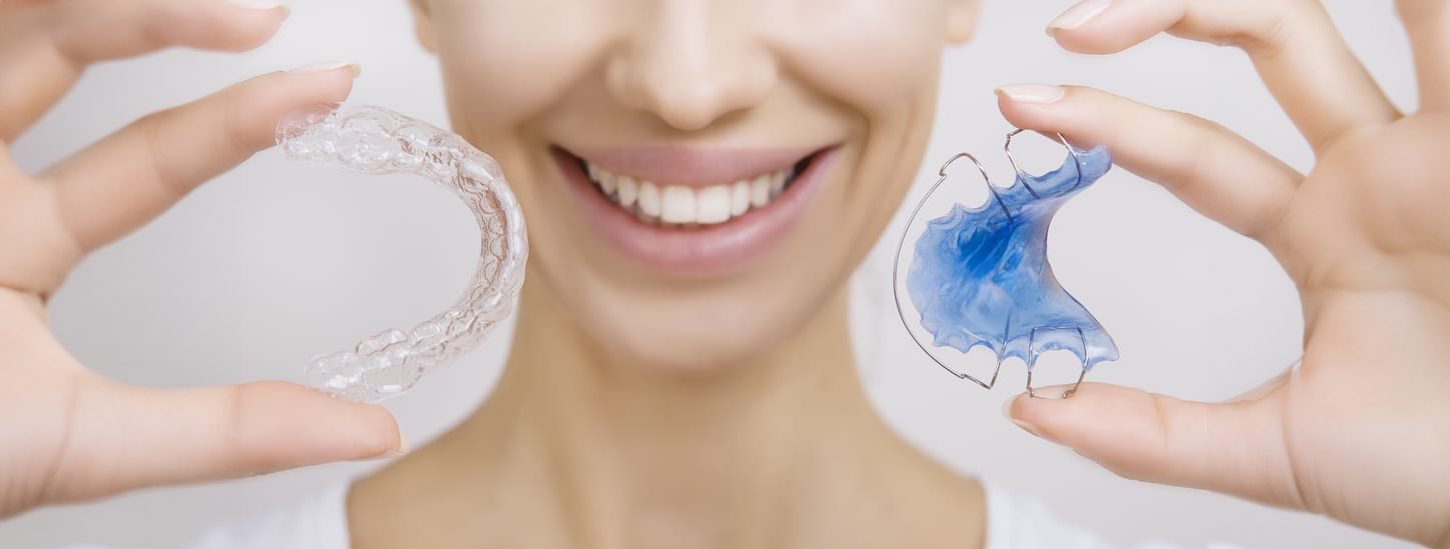 A woman holding traditional and clear retainers