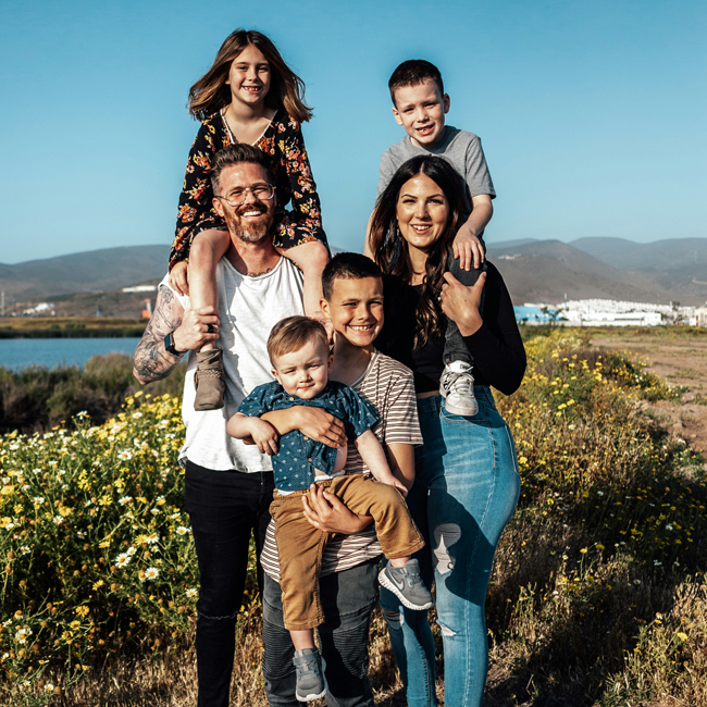 smiling family standing in front of river